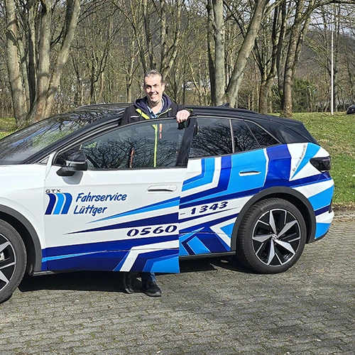 Marc Lüttger steht an der Tür eines E-Autos