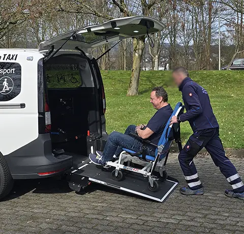 Fahrer von Fahrservice Lüttger bringt Mann mit Tragestuhl in ein Auto